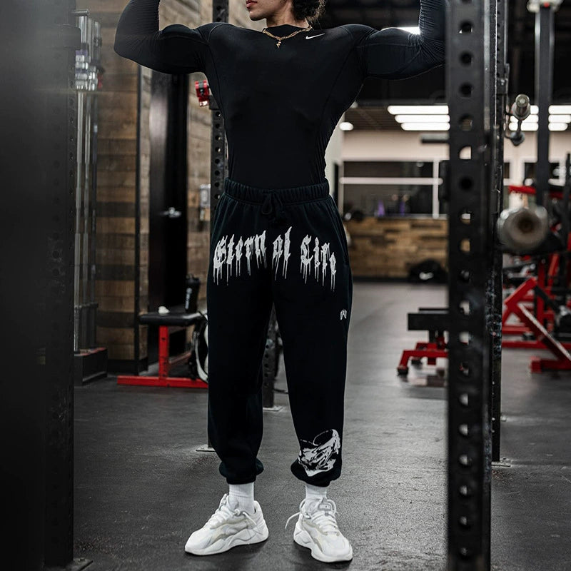 Pantalones deportivos holgados con estampado de calaveras oscuras y tobillos atados para entrenamiento muscular.