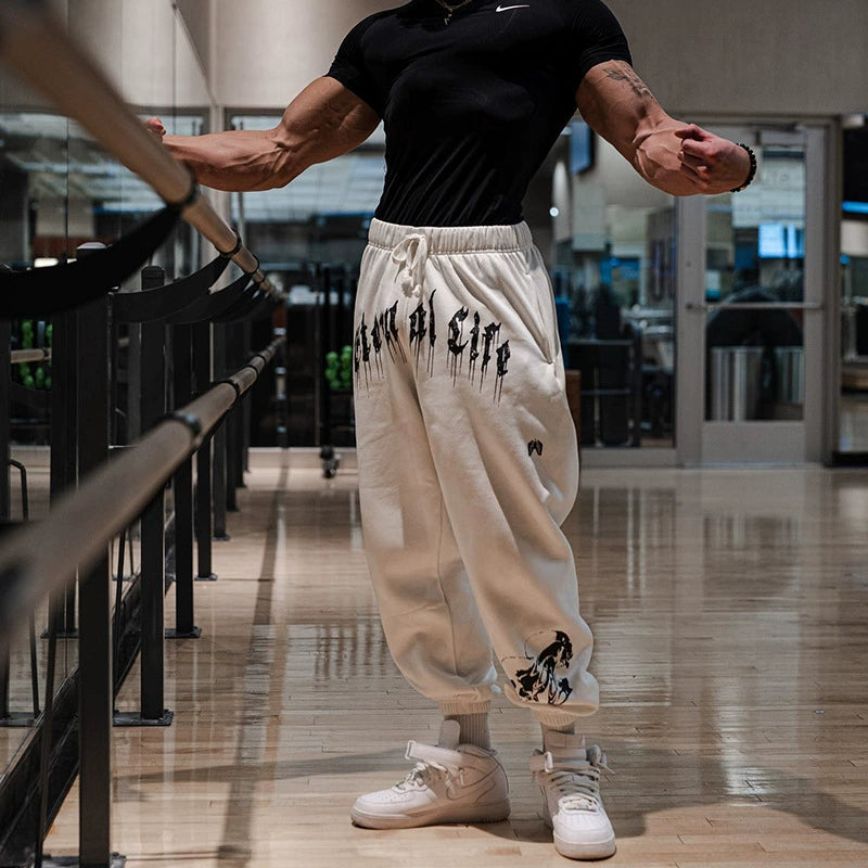 Pantalones deportivos holgados con estampado de calaveras oscuras y tobillos atados para entrenamiento muscular.
