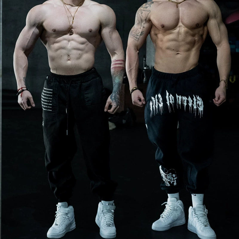 Pantalones deportivos holgados con estampado de calaveras oscuras y tobillos atados para entrenamiento muscular.