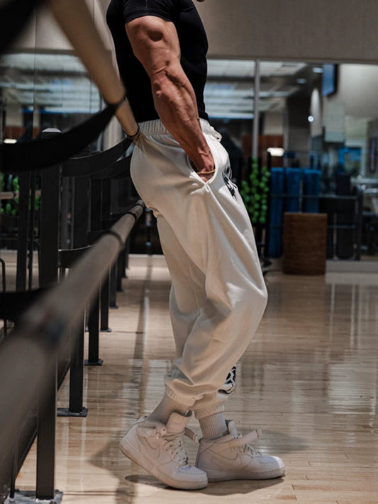 Pantalones deportivos holgados con estampado de calaveras oscuras y tobillos atados para entrenamiento muscular.